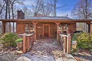 A rustic cabin with a wooden porch, a chimney, and a sign indicating it is a "Sawmill."