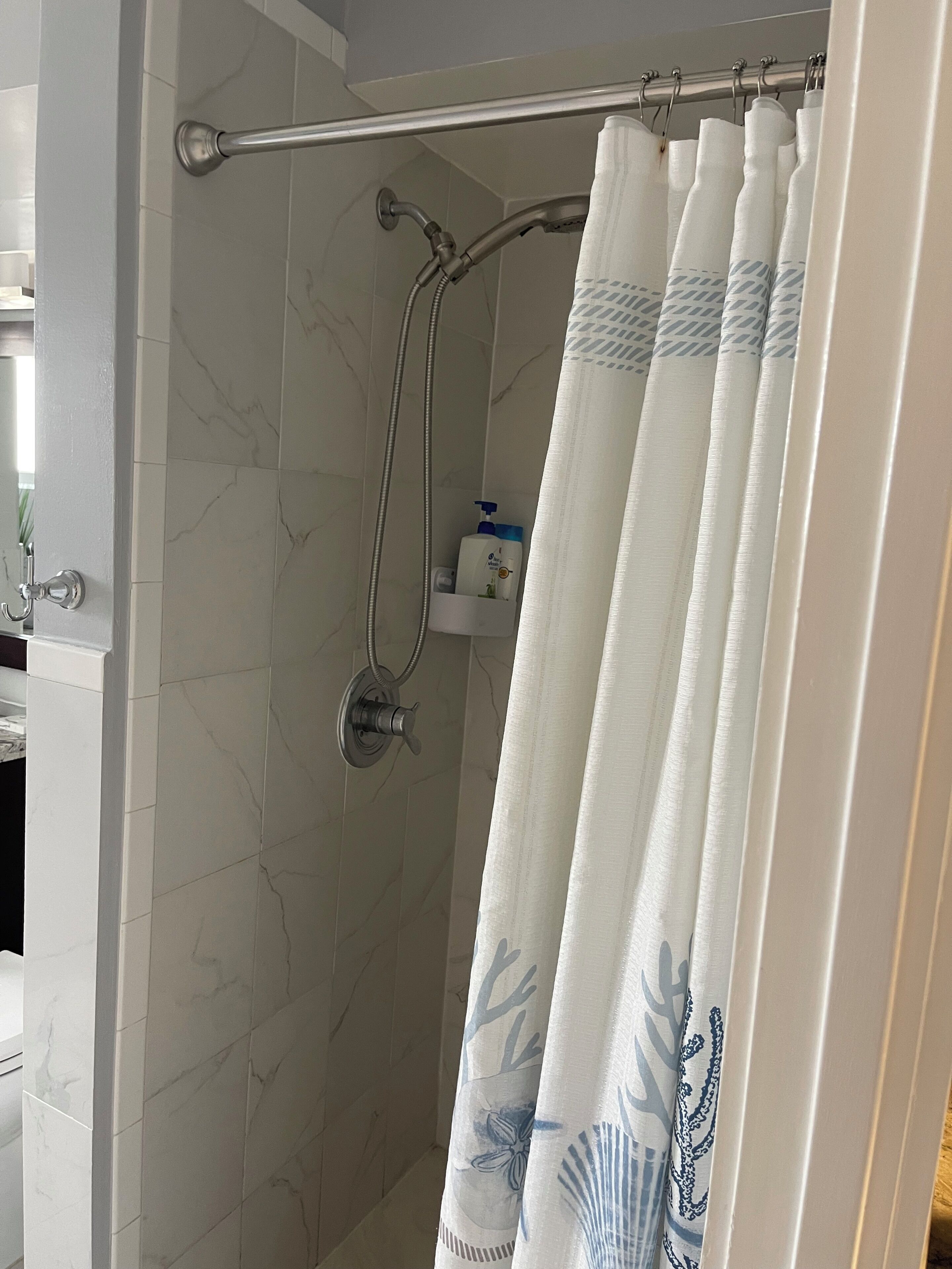 A shower with a glass door, a towel rack, and a showerhead.