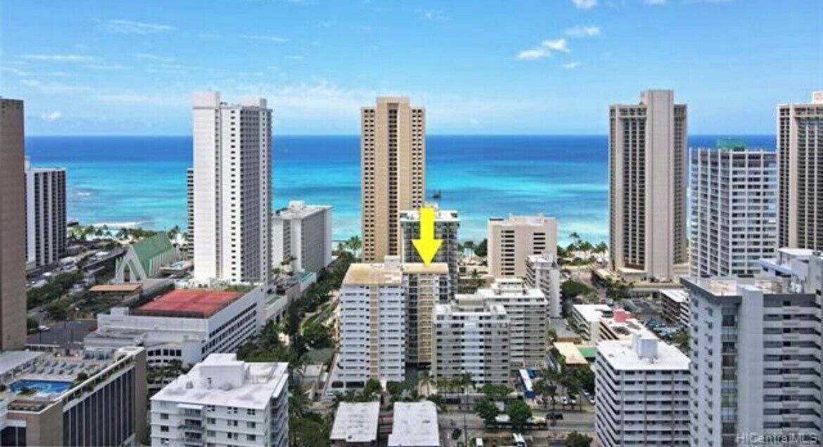 A high-rise hotel with multiple floors, a central atrium, and a view of the ocean.