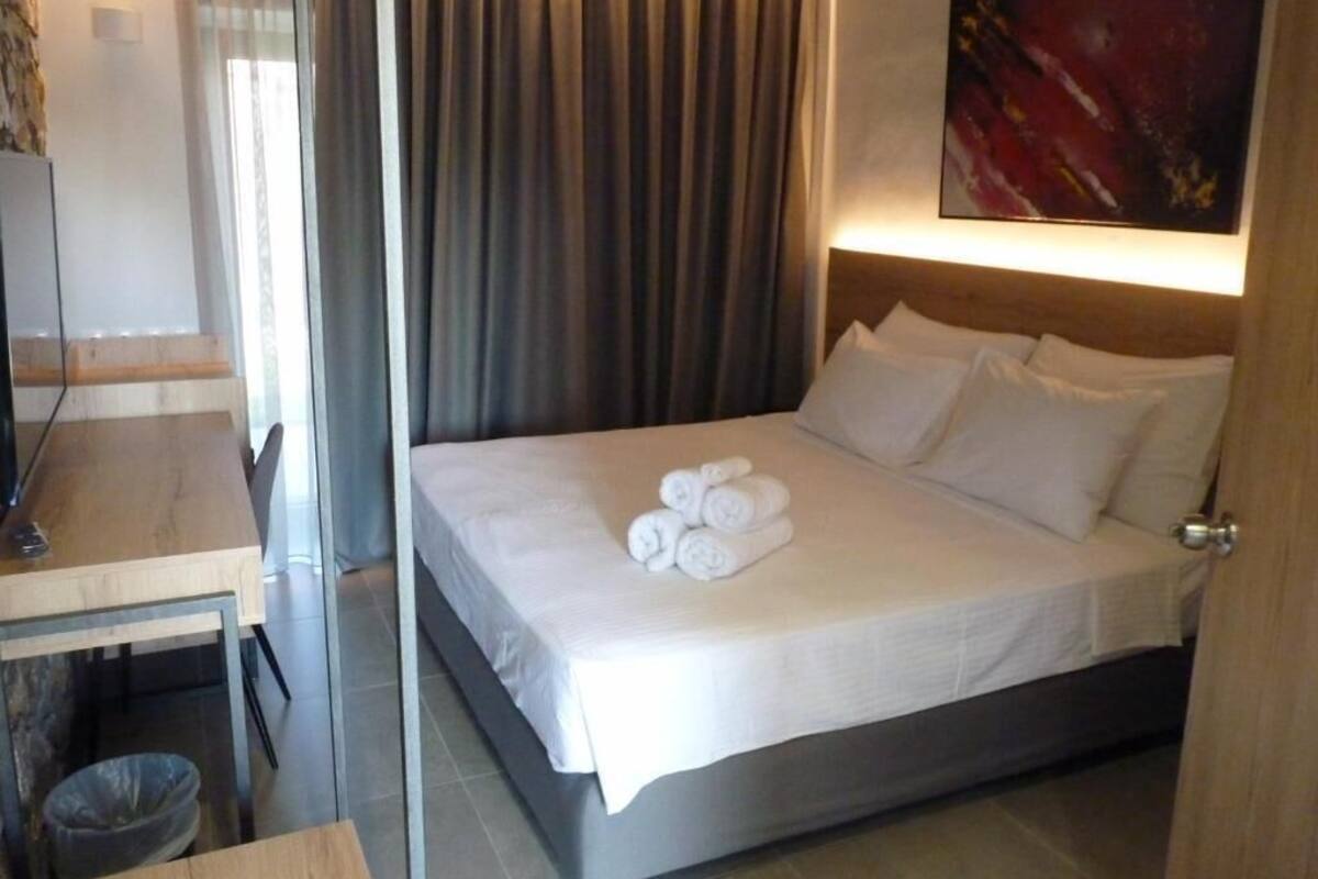 A hotel room with a bed, a desk, a chair, a TV, and a painting on the wall.