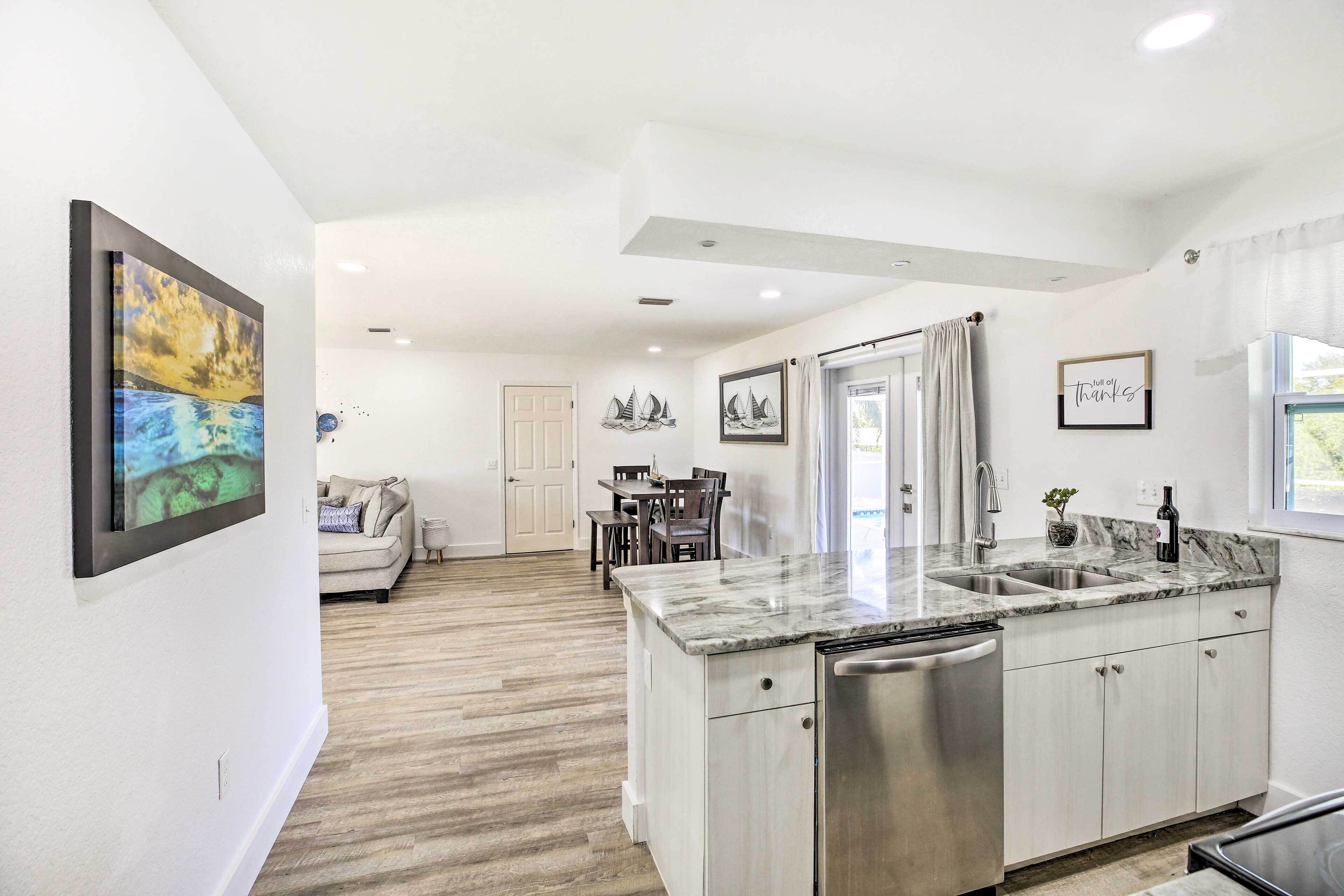 A modern kitchen with a marble countertop, stainless steel appliances, and a dining area with a table and chairs.