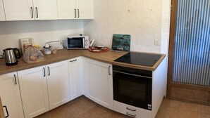 Une cuisine compacte avec des meubles blancs, un four à micro-ondes, un grille-pain et un petit four.