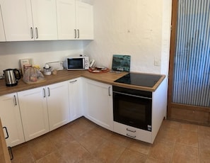 Une cuisine compacte avec des meubles blancs, un four à micro-ondes, un grille-pain et un petit four.