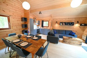A wooden cabin interior with a dining area, kitchen, and living space. - Log Cabin in Oignies with Barbecue (Oignies en Thiérache)