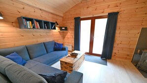 A cozy living room with a blue sofa, a wooden coffee table, and a bookshelf against the wall.