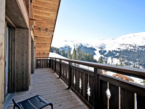 Un balcón de madera con vistas a montañas nevadas.