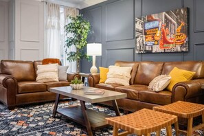 Een zithoek met twee bruine leren banken, een salontafel en een vloerkleed met dessin.