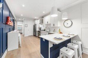 Una cocina moderna con armarios blancos, una isla central e iluminación colgante.