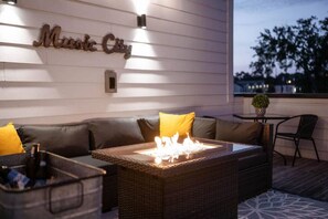 A cozy outdoor seating area with a wicker table, cushions, and a wall-mounted sign. - BRAND NEW LISTING downtown Nashville - Nashtopia! (Nashville)