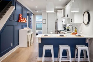 Een moderne keuken met een centraal eiland, barstoelen en een trap.