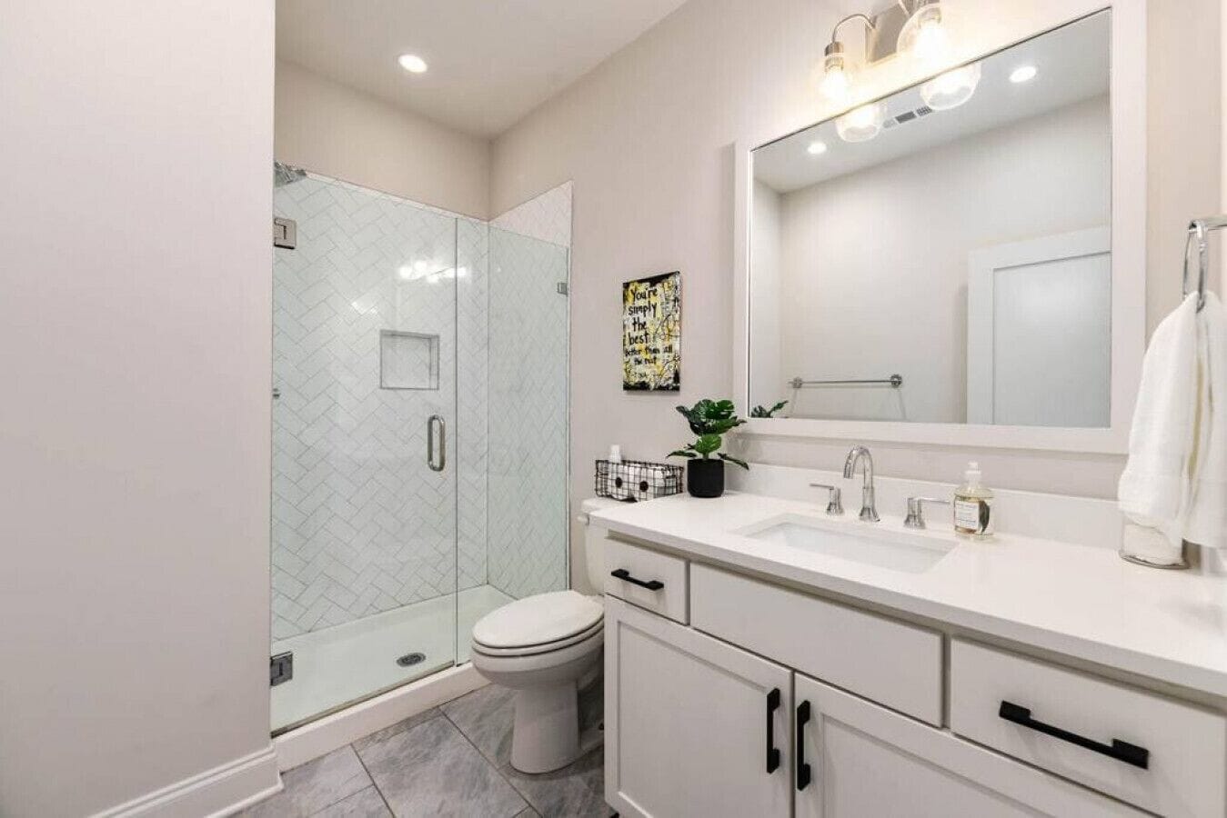Une salle de bain moderne avec une douche à parois de verre, des toilettes, un lavabo avec un miroir et un meuble de rangement.