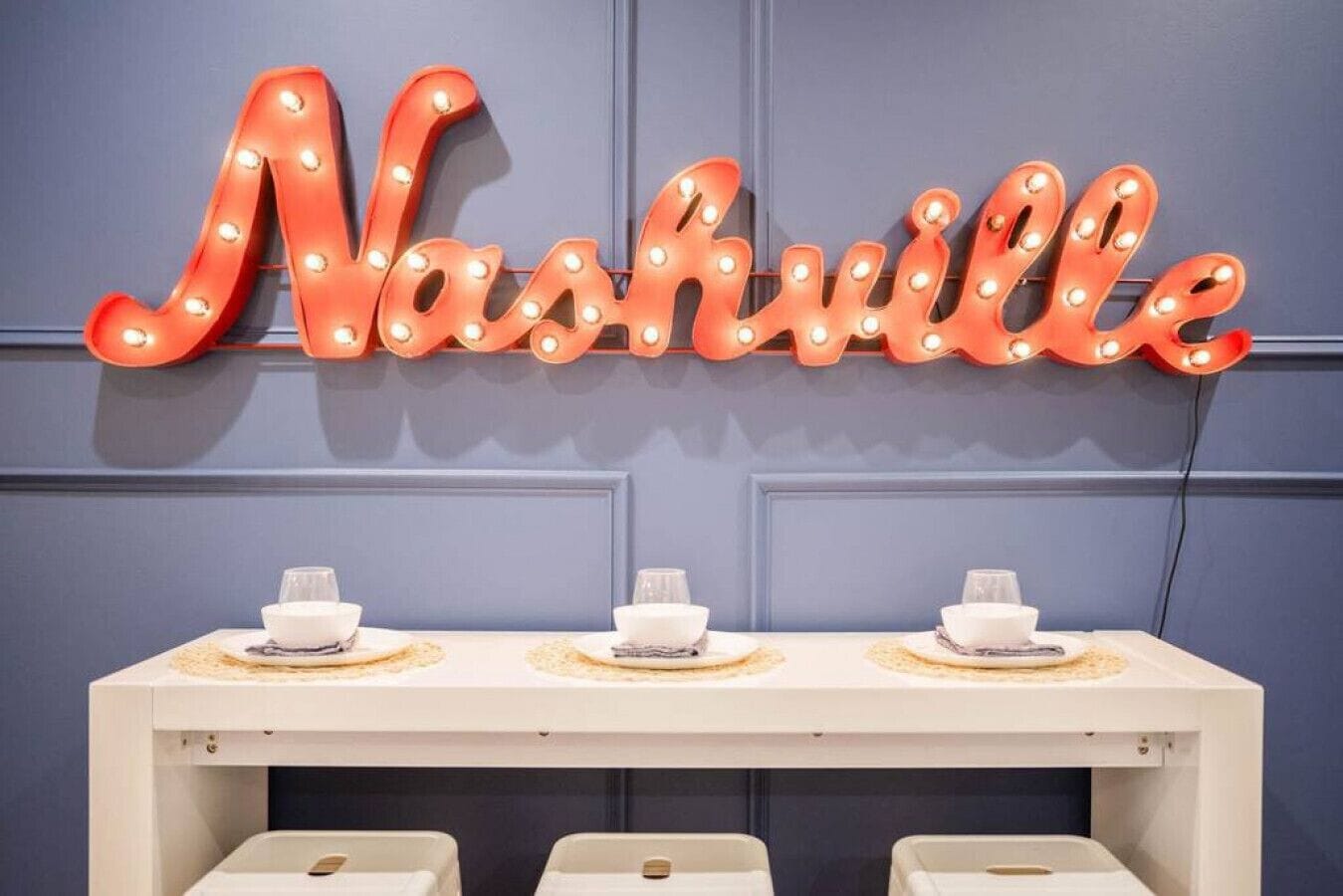 Ein Neonzeichen mit dem Schriftzug 'Nashville' über einem Esstisch.
