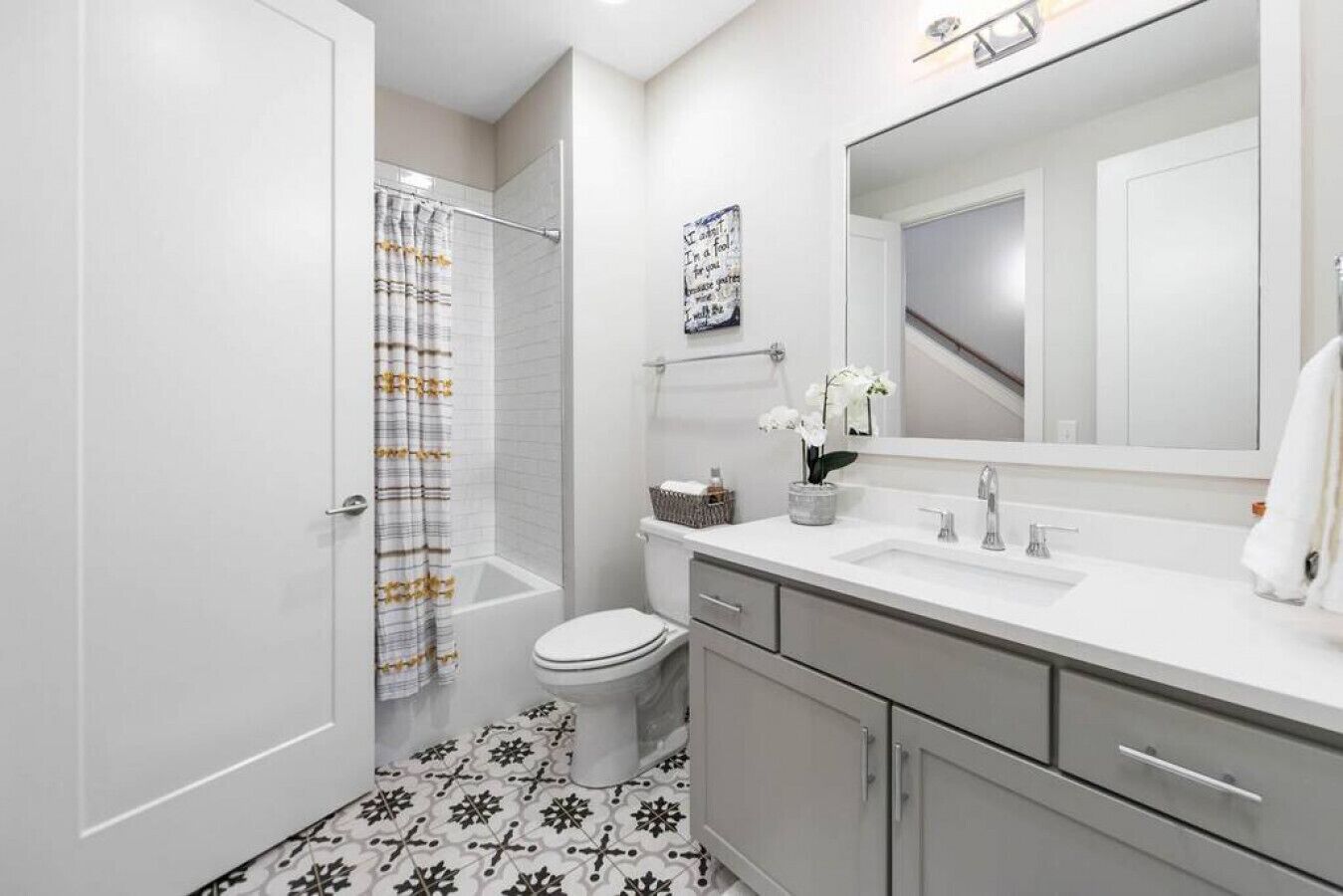 A bathroom with a shower, toilet, vanity, and a large mirror.
