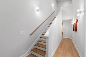Un escalier avec des marches en bois et une rampe, menant à une pièce dont le plancher est de couleur claire.