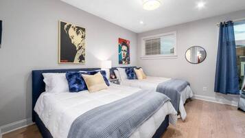 A bedroom with two beds, a large mirror, and artwork on the walls.
