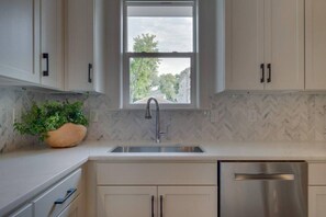Una cocina con ventana, un fregadero, armarios y lavavajillas.