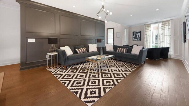 Ein modernes Wohnzimmer mit einem Ecksofa, einem Couchtisch und einem gemusterten Teppich.