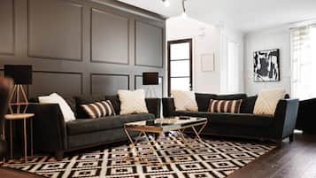 Una sala moderna con un sofá oscuro, un tapete estampado y una mesa de centro minimalista.