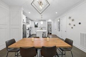 A modern kitchen with white cabinetry, a wooden dining table, and black chairs. - Rooftop & Games Rm in Heart of Downtown - 12 Beds! (Nashville)