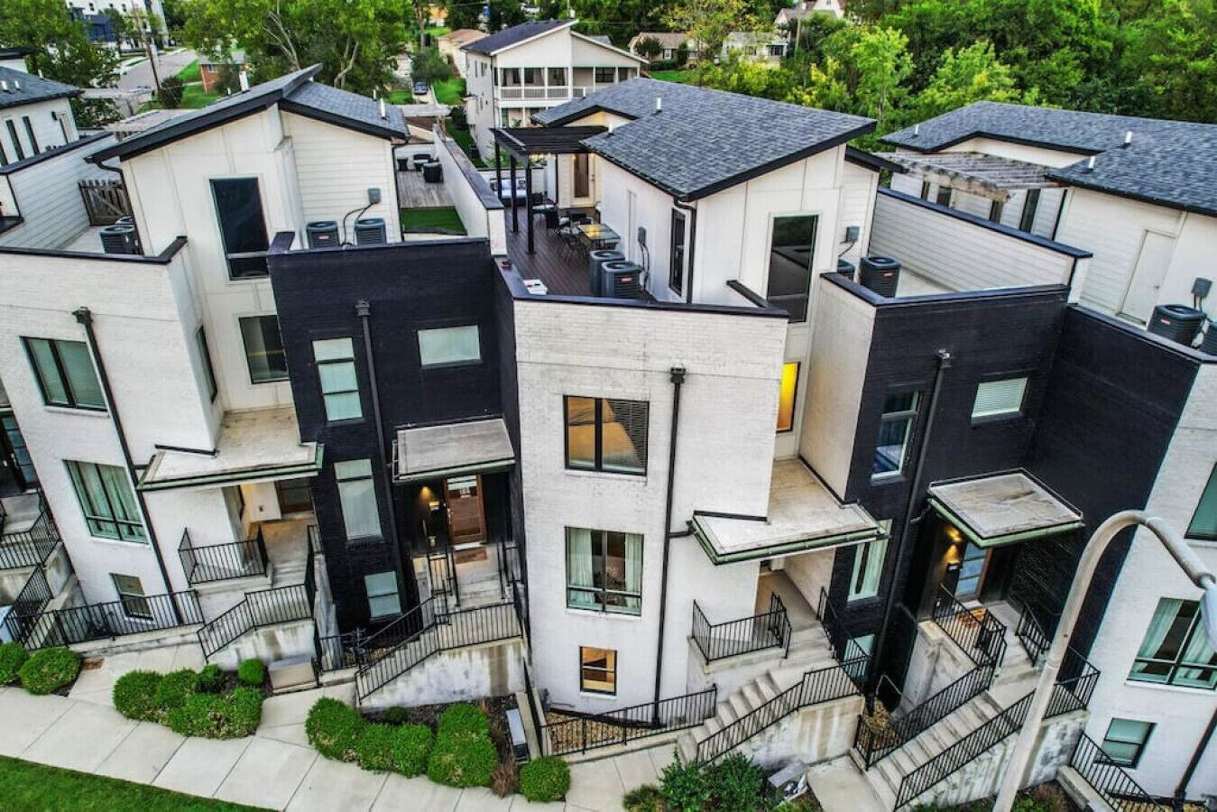 Un immeuble résidentiel moderne à plusieurs étages, avec une façade combinant des murs blancs et foncés, de nombreux balcons et une cour intérieure.