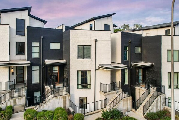 Un immeuble résidentiel moderne à la façade symétrique, doté de nombreux balcons et d’une cour intérieure.