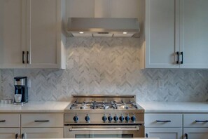 A kitchen with a gas stove, oven, and a coffee maker on the counter.