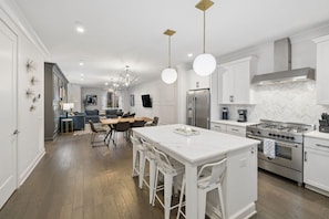 A modern kitchen with white cabinetry, a central island, stainless steel appliances, and pendant lighting. - Rooftop & Games Rm in Heart of Downtown - 12 Beds! (Nashville)