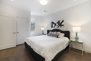 Une chambre à coucher avec un grand lit, deux tables de chevet, une porte et une fenêtre.