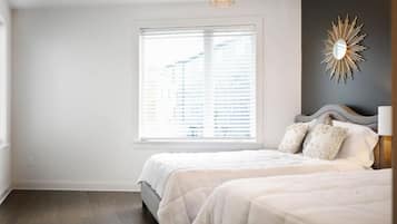 Un dormitorio con un ventanal grande, una cama y un espejo fijado a la pared.