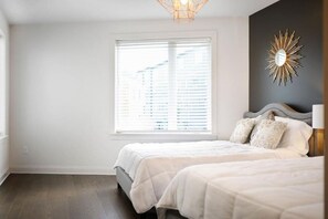Un dormitorio con un ventanal grande, una cama y un espejo fijado a la pared.