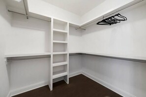 A corner closet with white walls, a metal ladder, and a black hanger rack.