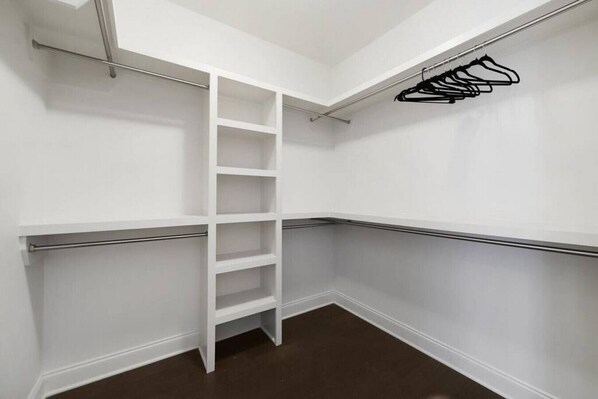 A corner closet with white walls, a metal ladder, and a black hanger rack.