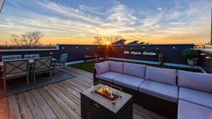 Una terraza en la azotea con un hogar para fuego, mobiliario exterior y un letrero de neón que dice 'The English Garden'.