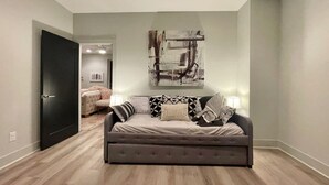 Una sala de estar moderna con un sofá gris, un cuadro abstracto grande y suelo de madera.