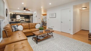 A modern living room with a leather sectional sofa, a coffee table, and a dining area in the background.