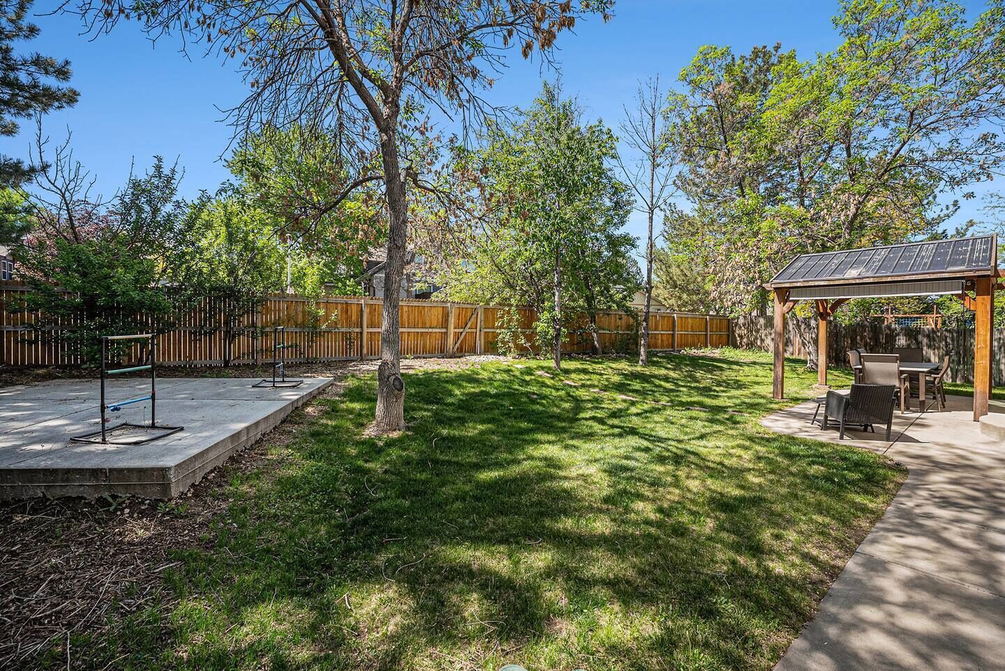 A backyard with a patio, a pergola, and a fenced area.
