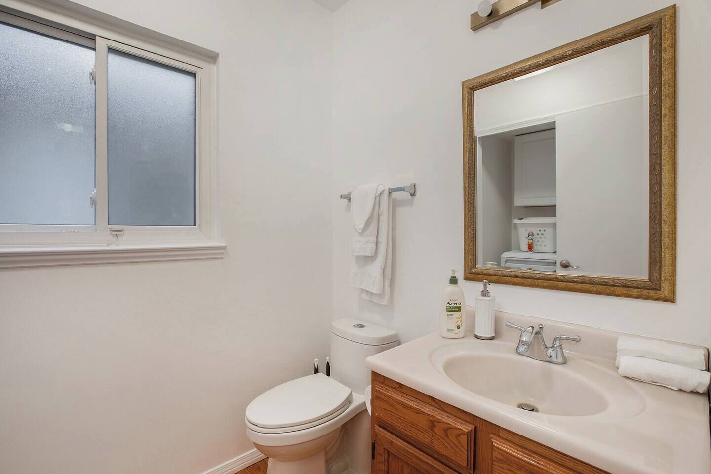 Une salle de bain avec des toilettes, un lavabo, un miroir et une fenêtre.