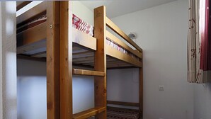 Een kamer met drie stapelbedden, houten wanden en een radiator.