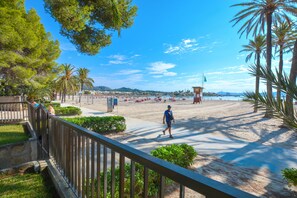 Une plage avec une promenade en bois, des palmiers et un poste de surveillance pour les sauveteurs.