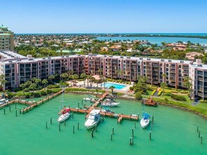 A marina with boats docked, a swimming pool, and a hotel with multiple floors and balconies. - Waterfront 1BR condo in Marco Island with pool, Wi-Fi, and marina access. (Marco Island)