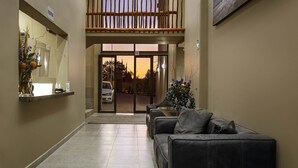 Ein Empfangsbereich mit Rezeption, einer Wartezone inklusive Sofa, einem Balkon und einem großen Fenster.