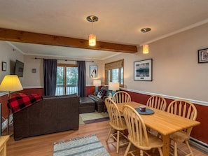 A cozy room with a wooden dining table, chairs, a sofa, and a TV.