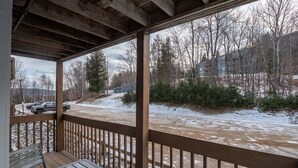 A covered outdoor area with a wooden deck, a table, and a bench.