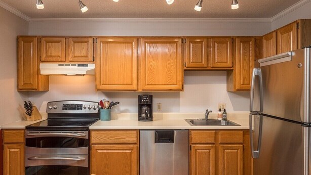 A kitchen with wooden cabinets, stainless steel appliances, a coffee maker, and a dishwasher.