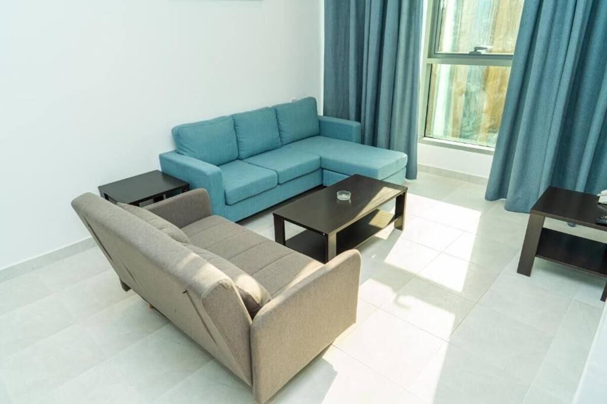 A living room with a light blue sectional sofa, a smaller sofa, a coffee table, and two side tables.
