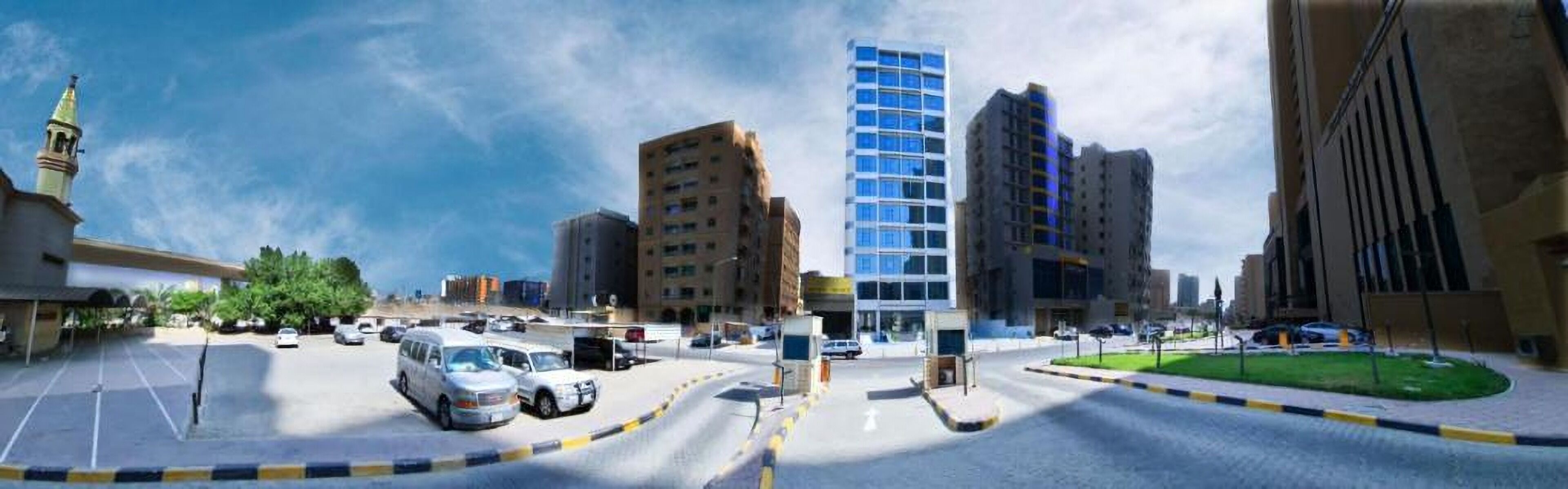 Un paisaje urbano con edificios modernos, un estacionamiento y una mezquita con un minarete.