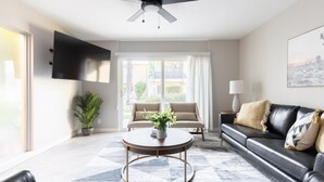 Ein modernes Wohnzimmer mit einer Couch, einem Couchtisch und einem an der Wand befestigten Fernseher.