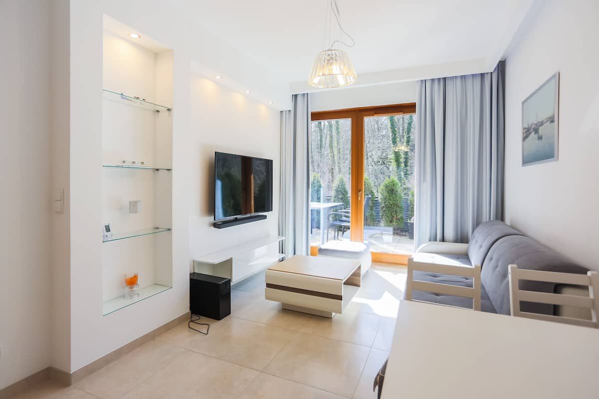 A modern living room with a flat-screen TV, glass shelves, a sofa, and a dining table.