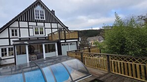 Una casa tradicional de entramado de madera con balcón visible y piscina.