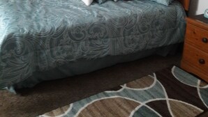 Um quarto com cama, penteadeira, mesa de cabeceira e espelho.